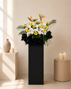 Fallen Petals Condolences Flower Stand with yellow gerberas, sunflowers and bird of paradise, front view