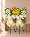 Verdant Whisper Condolences Flower Stand with yellow gerberas, papermums and champagne roses, full arrangement